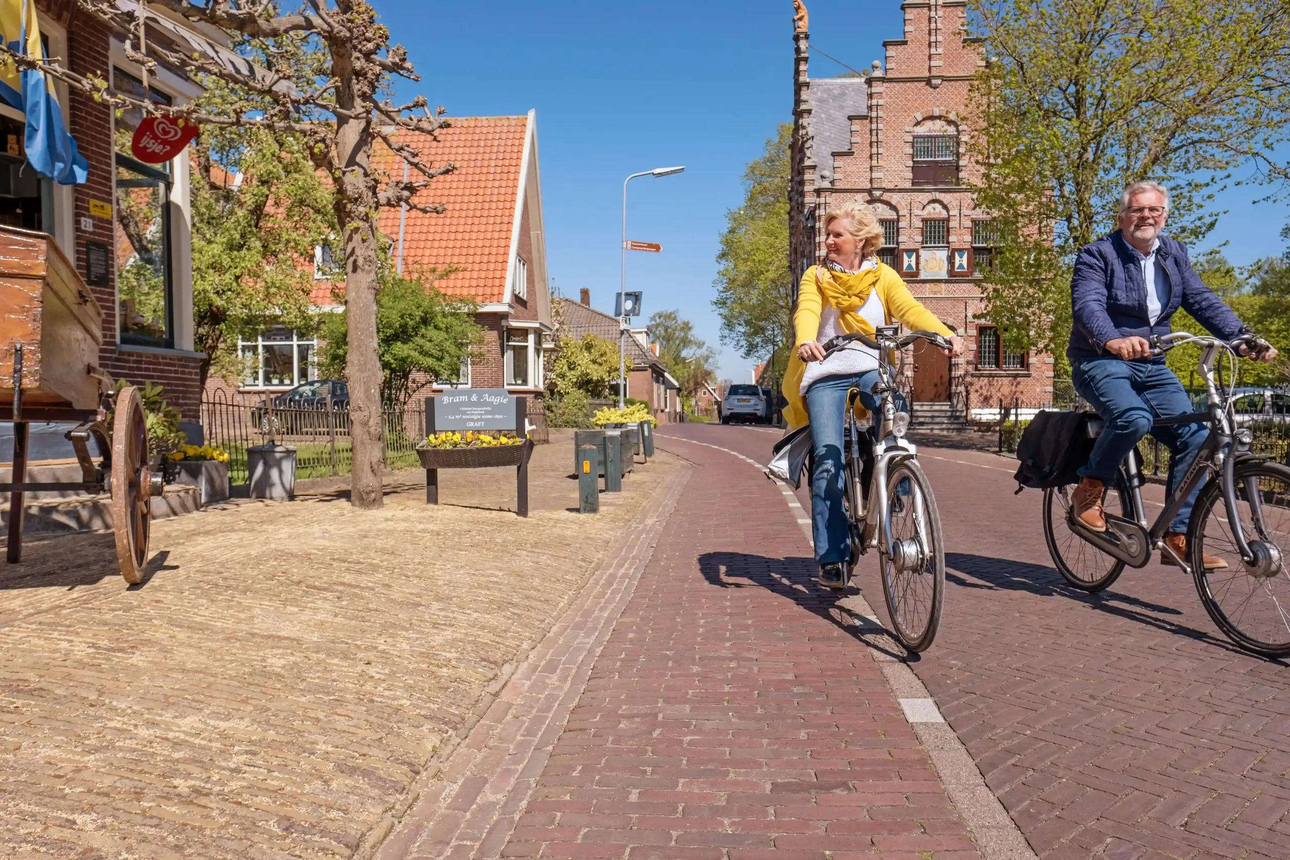 Man en vrouw op de fiets langs het raadhuis de Rijp
